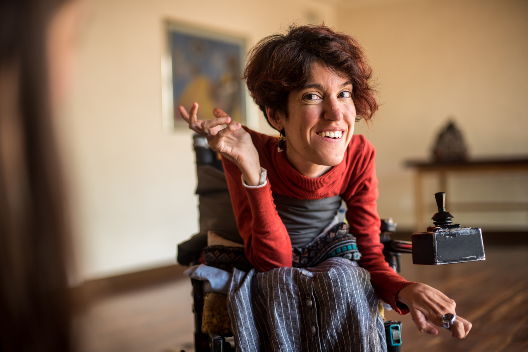 A person in a wheelchair smiling while holding a remote control