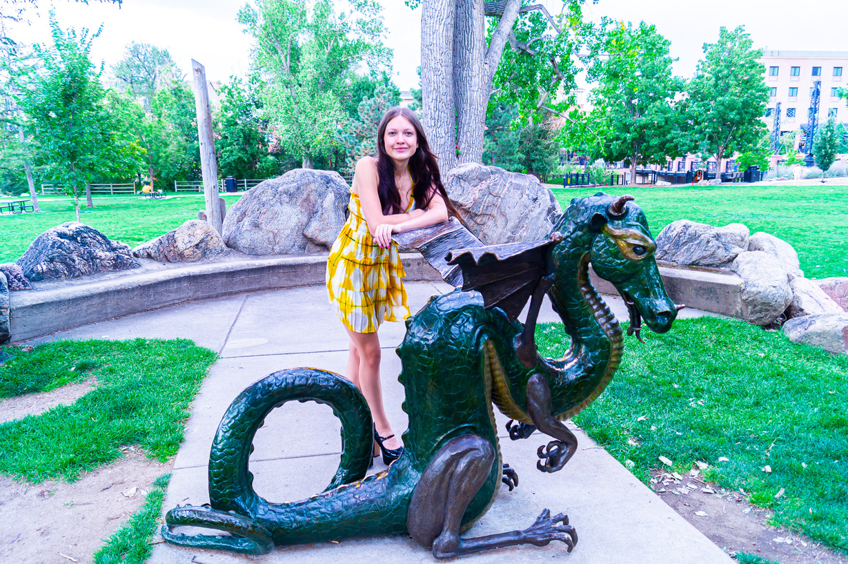 a person is posing next to a statue of a dragon