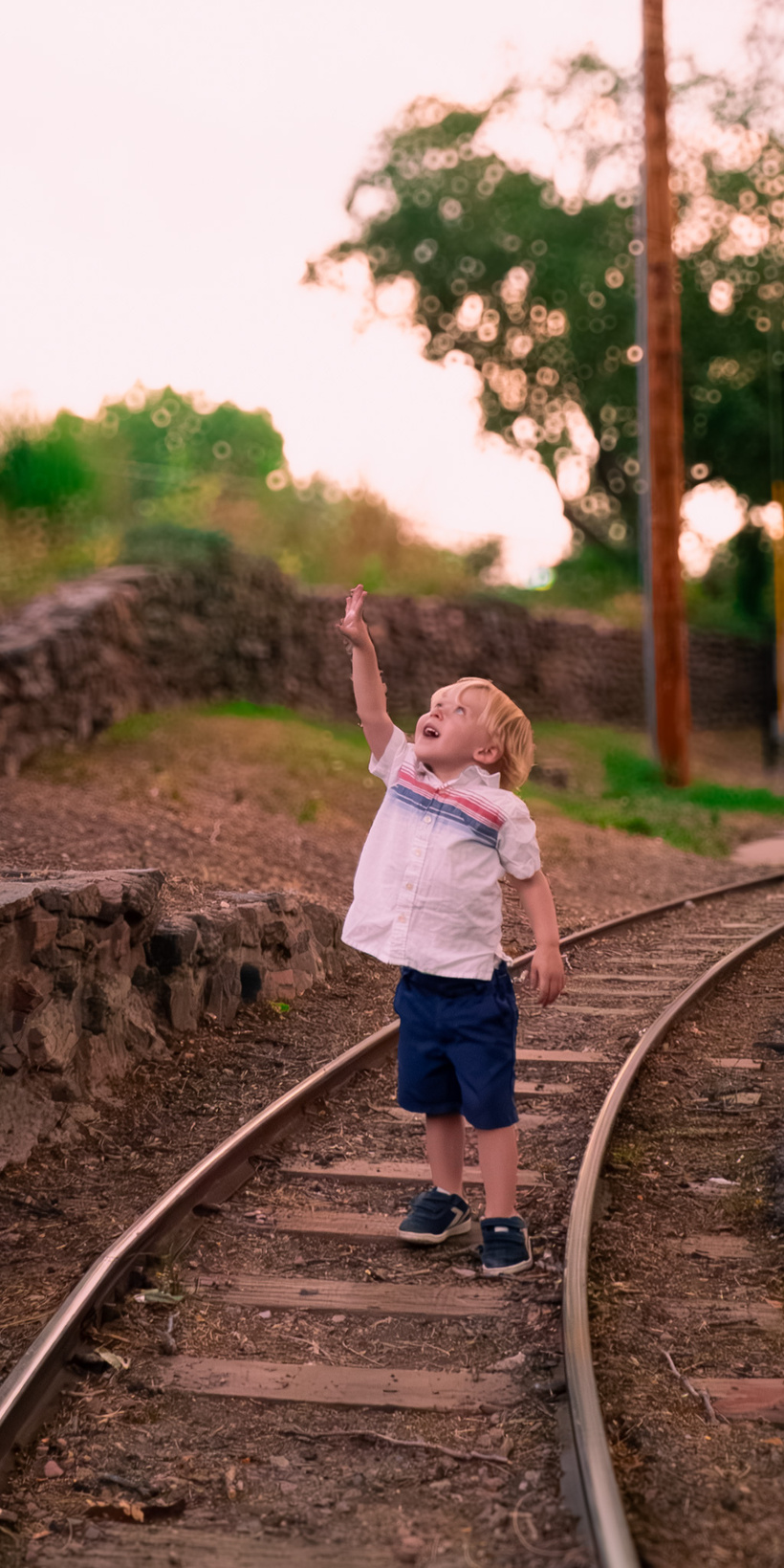 a child standing on a train track with their hand up in the air