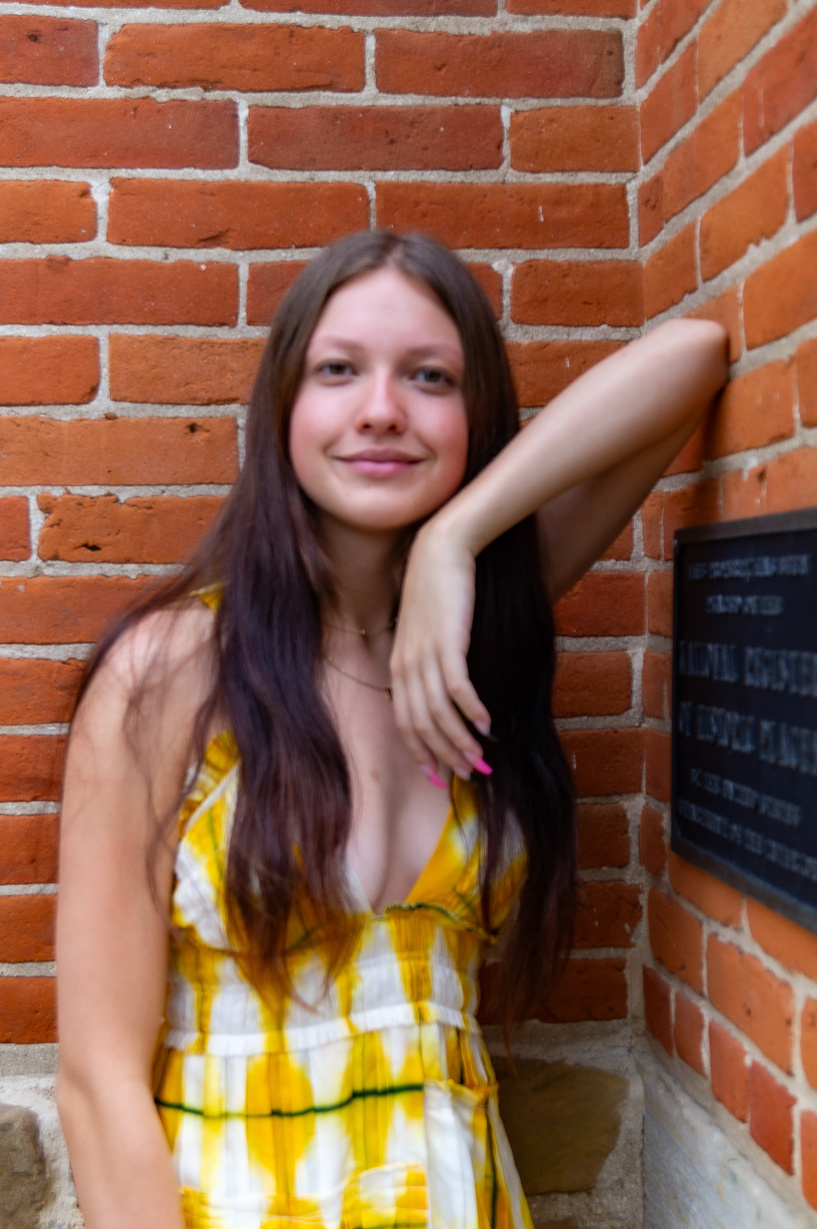 a person in a yellow dress standing next to a brick wall