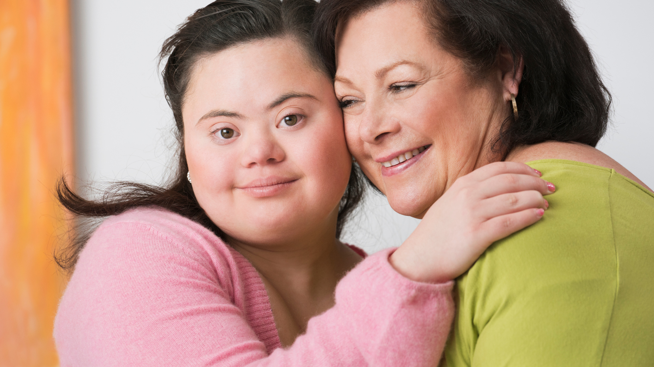 A person hugging another person with Down syndrome