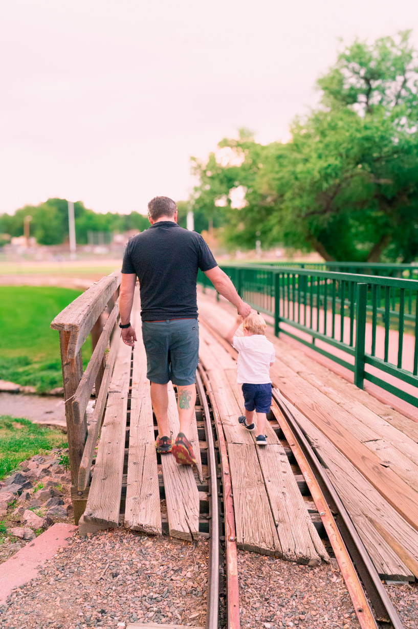 a parent and child walking across a wooden bridge