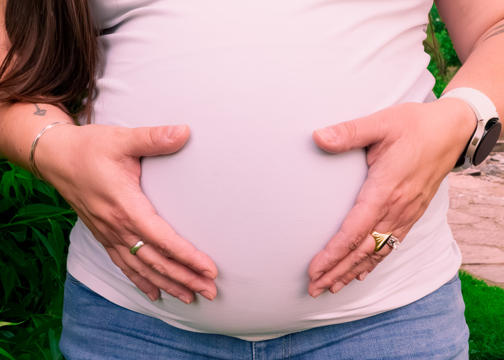 a woman with their hands on their pregnant belly