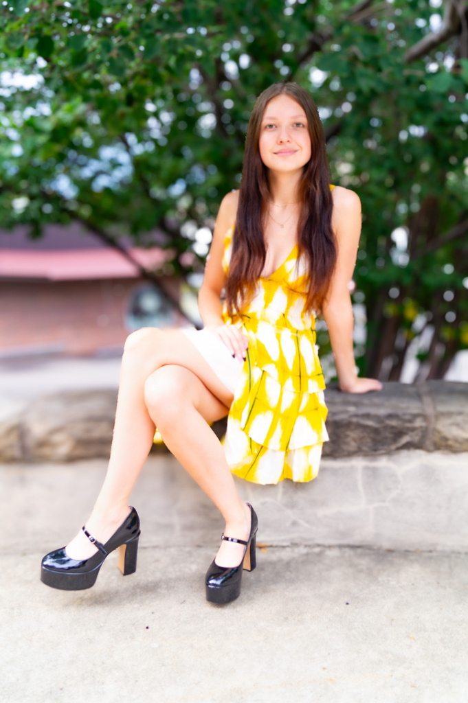 a person in a yellow dress sitting on a ledge