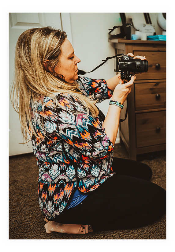 A person holding a camera while sitting on the floor