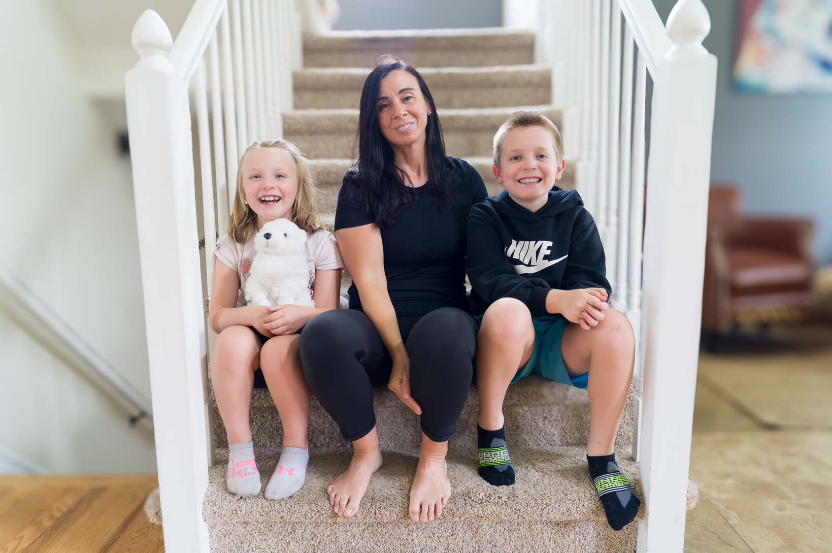 Two children sitting on stairs on either side of their mother