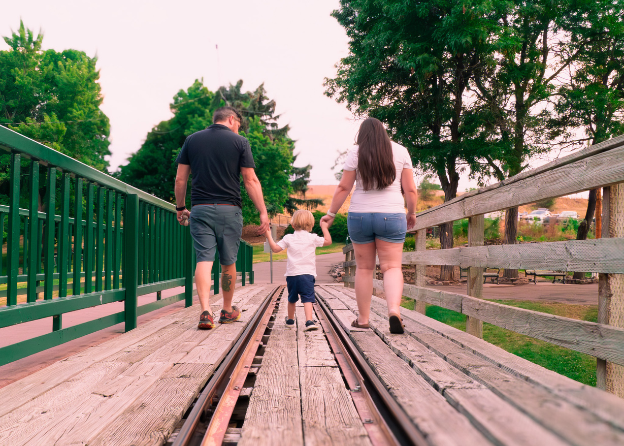 a family walking on a wooden bridge in a park