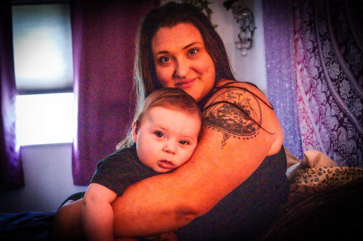 a person holding a baby with a tattoo on their arm