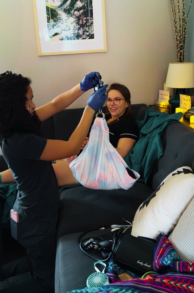 a midwife in a black shirt and blue gloves is weighing a baby 