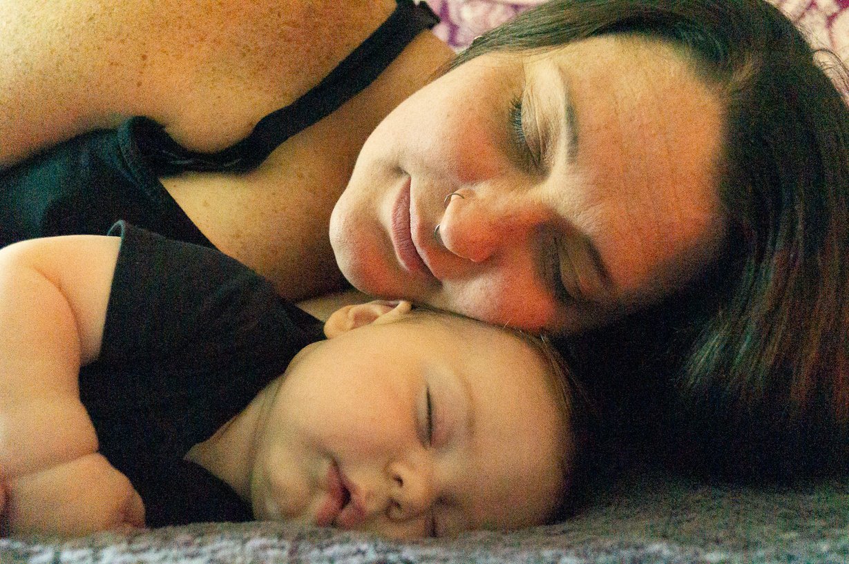 a person and a baby laying on a bed