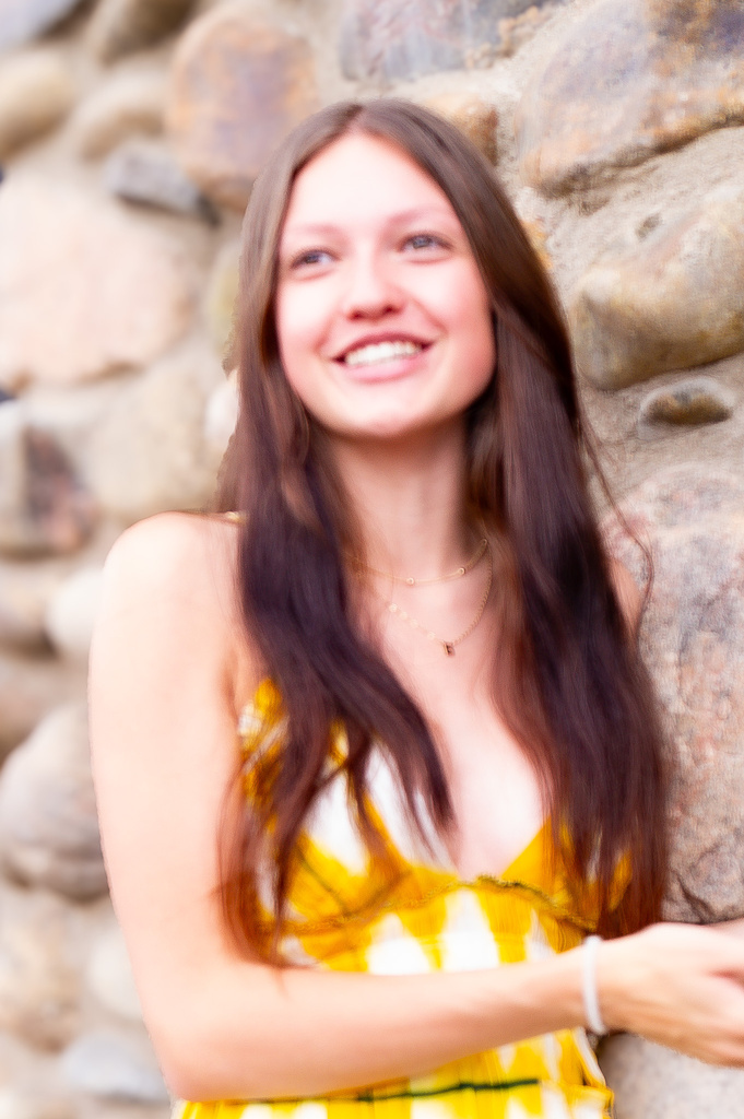 a person in a yellow tie dye dress smiling at the camera