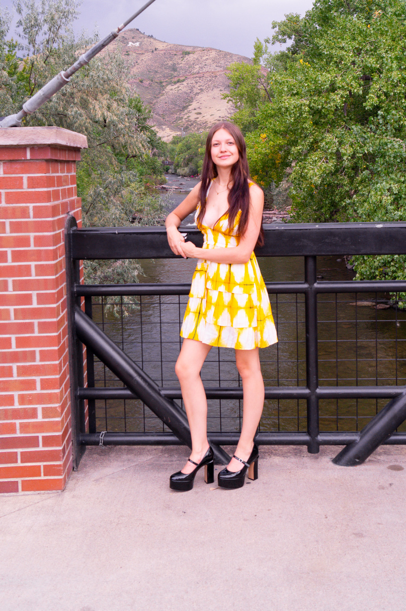 a person in a yellow dress standing on a bridge